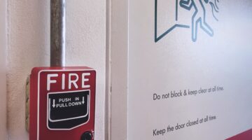Fire alarm with a fire safety sign posted on the wall next to it.