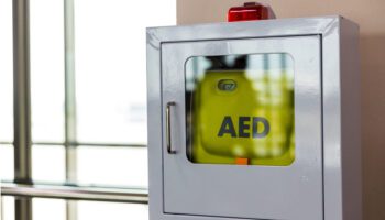 Automatic external defibrillator (AED) inside a wall-mounted cabinet.