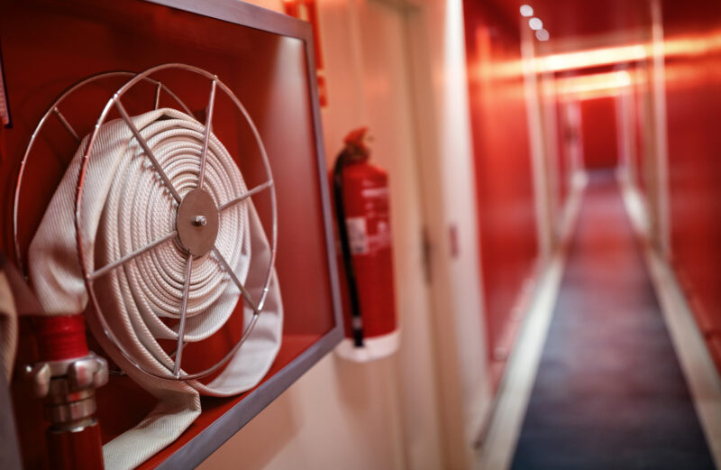 Fire hose and fire extinguisher on the wall of an office building hallway.