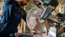 Carpenter cutting wood using a miter saw.