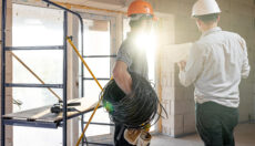 Two workers on a construction site looking over a document.