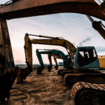 Excavators lined up in a row at a construction site.